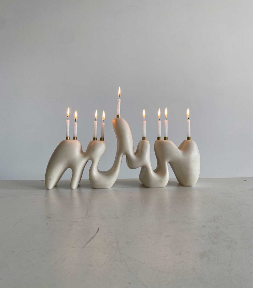 off-white modern curvy organic menorah with white candles lit