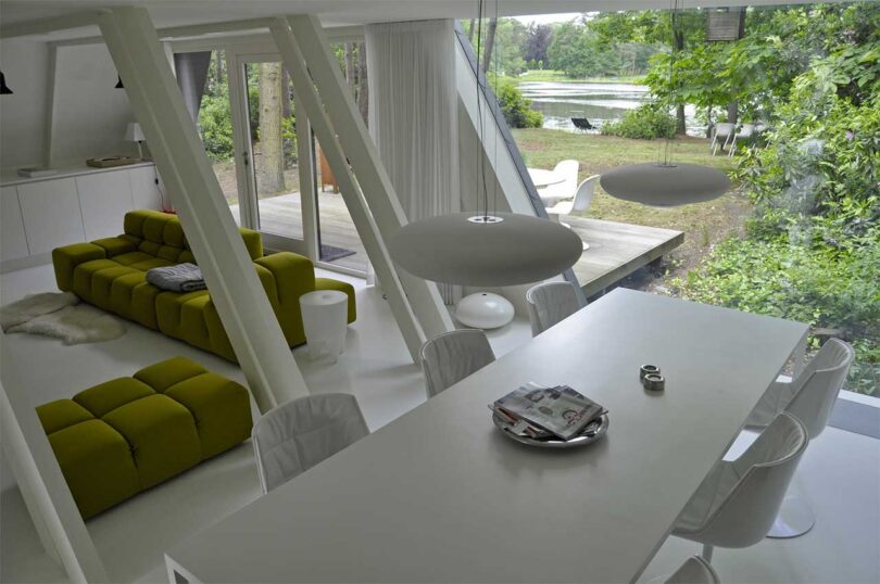 interior shot looking down at long white dining table with green sofa behind rafters