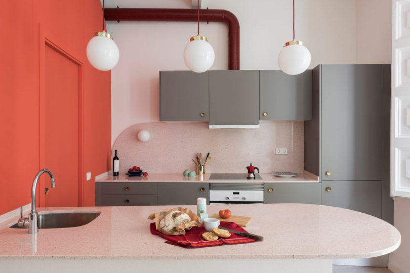 closeup of modern kitchen with grey cabinets, pink backsplash and orange structure