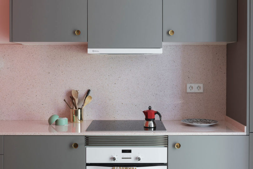 closeup of modern kitchen with grey cabinets and pink speckled backsplash and counter