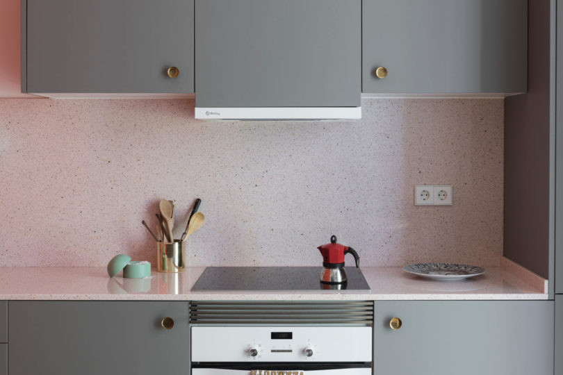 close-up da cozinha moderna com armários cinza e backsplash salpicado de rosa e balcão