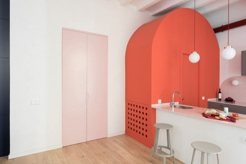 vista interior em ângulo do apartamento moderno com estrutura arqueada e portas cor de rosa