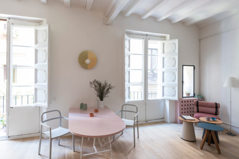 angled interior view of modern living space with pink dining table and seating