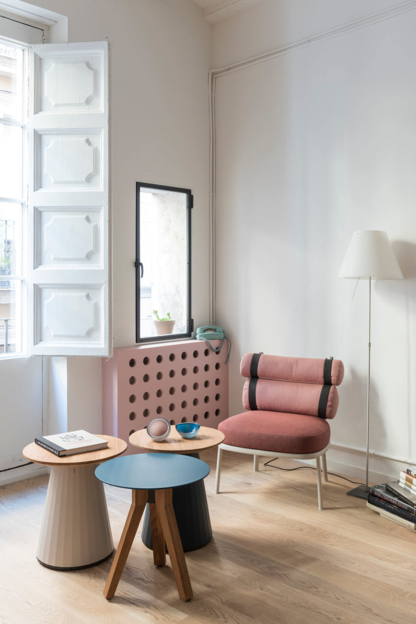closeup corner view in modern apartment with pink chair and trip of side tables