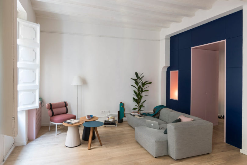 vista interior da moderna sala de estar com móveis cinza e rosa e uma parede azul marinho