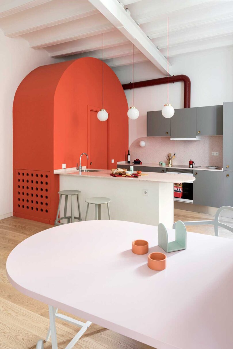 angled interior view of modern apartment with pink and orange kitchen