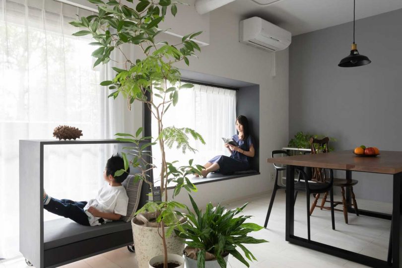 interior shot of modern apartment in dining room with women sitting in window frame and child sitting in rolling frame