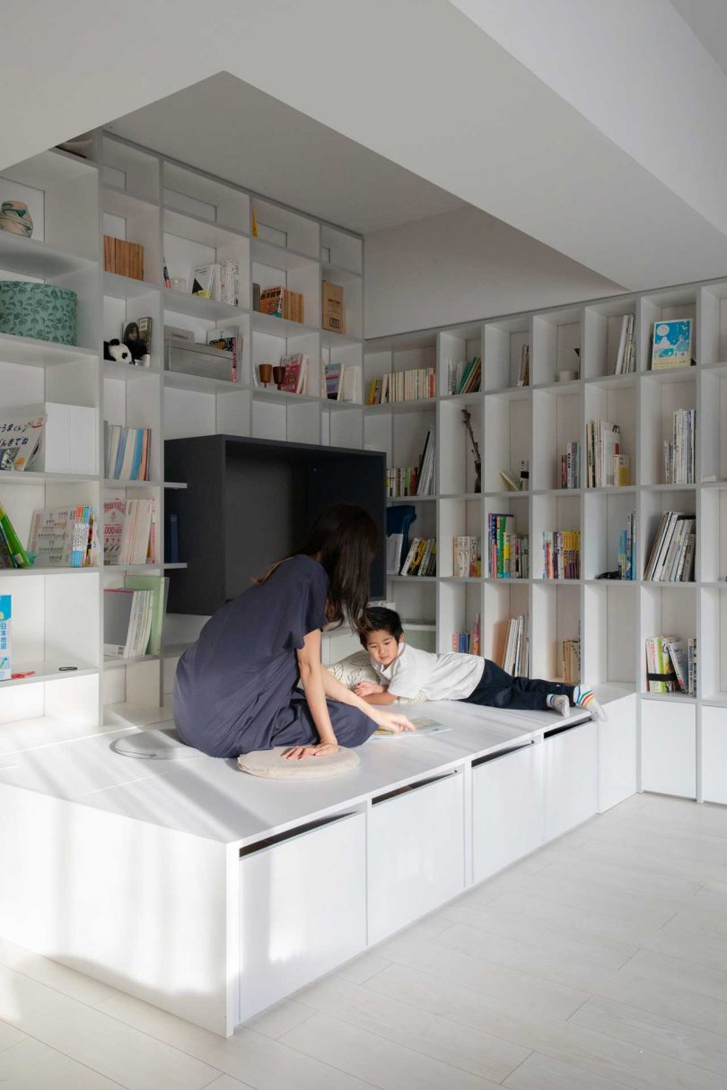 interior shot of modern apartment with two walls of bookcases and two people reading