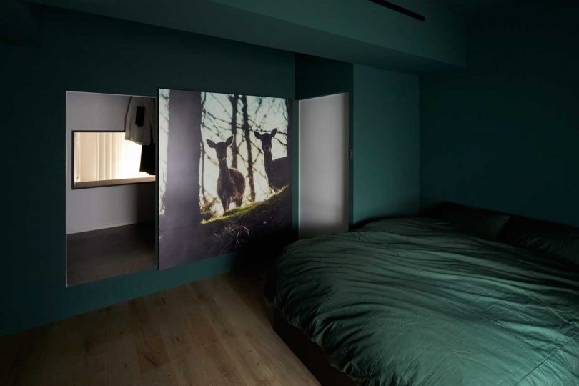 interior shot of modern apartment in dark green bedroom with two deer featured in artwork