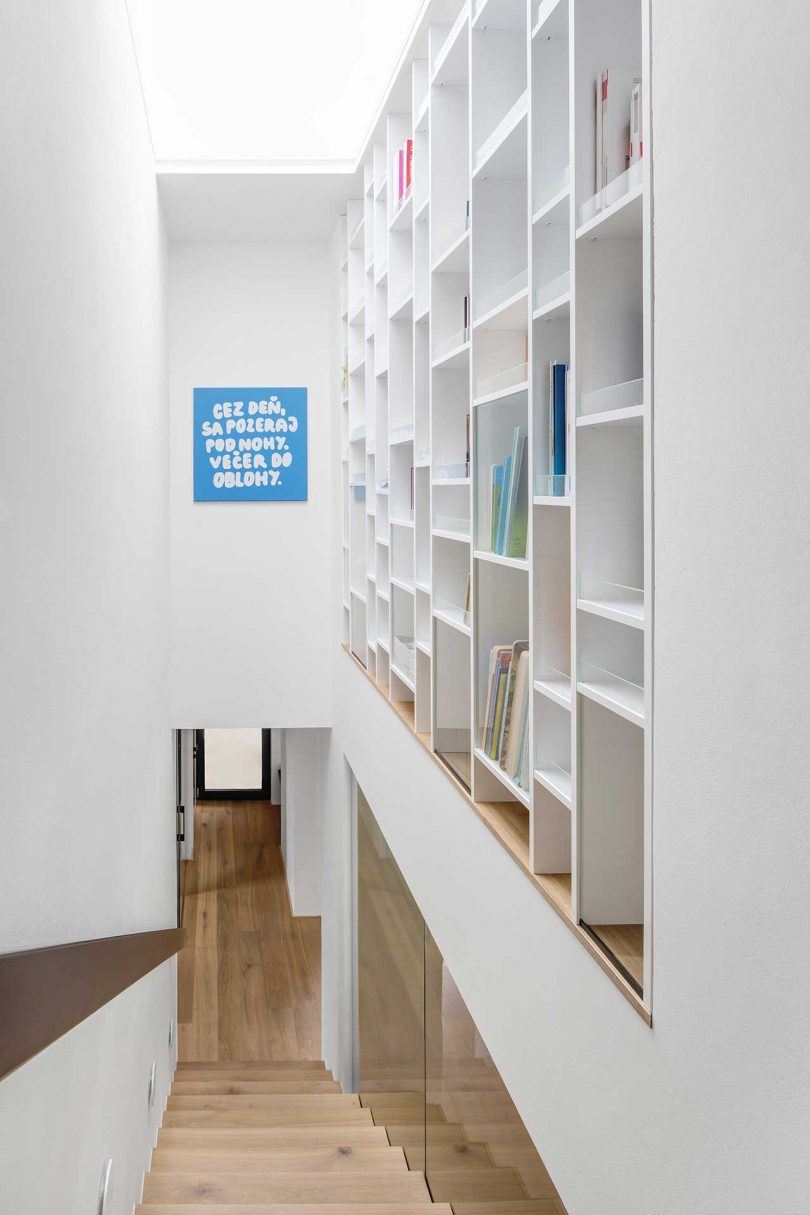 at the top of wooden staircase with wall of white bookshelves