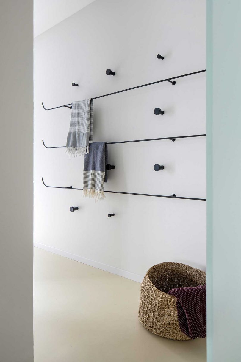 white wall with black hooks and bars to hang towels