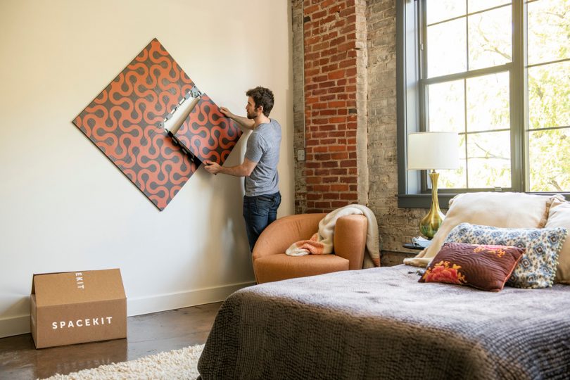 man installing art in bedroom