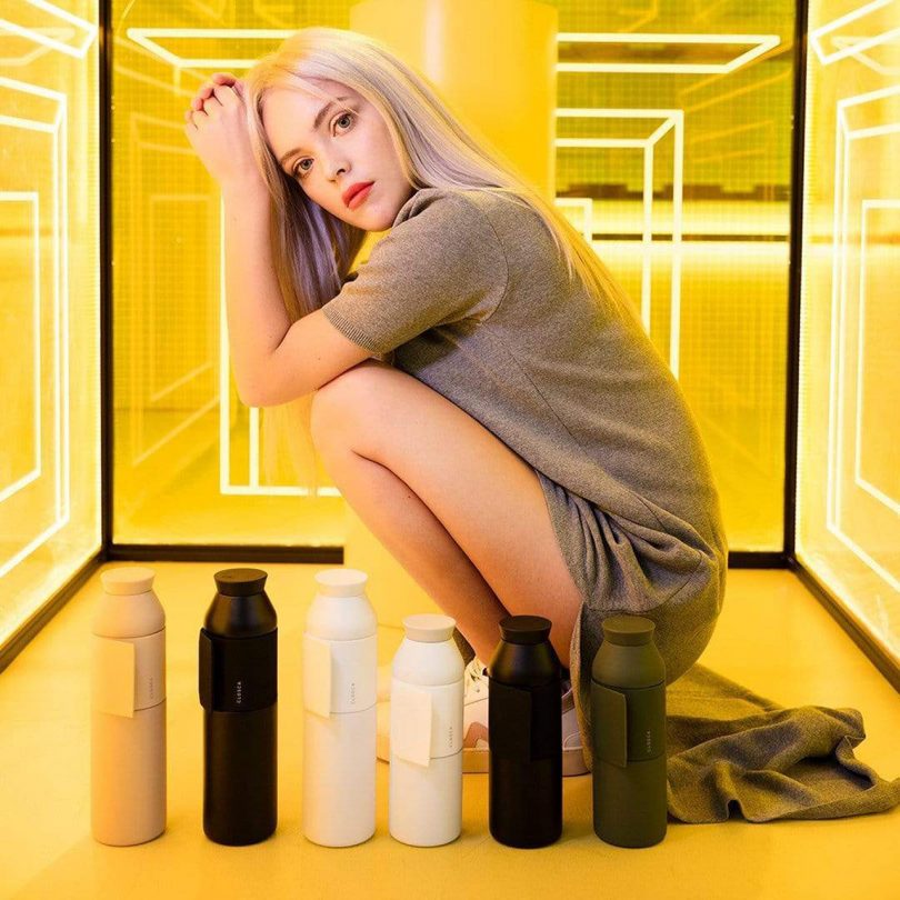 woman crouched next to six water bottles