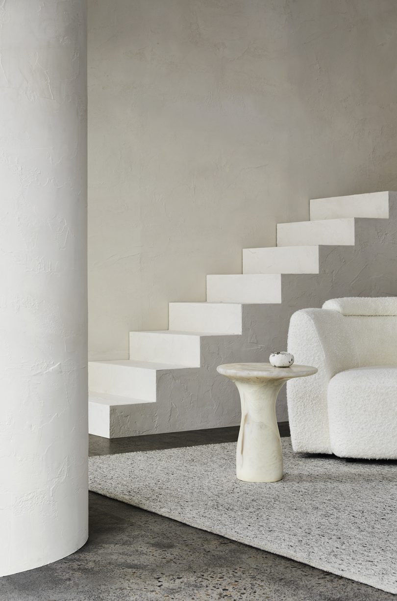 armchair and end table in front of staircase