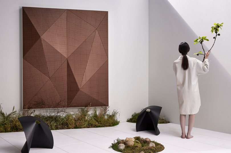 woman facing away from camera in a room with white walls and floor and faceted wall panels