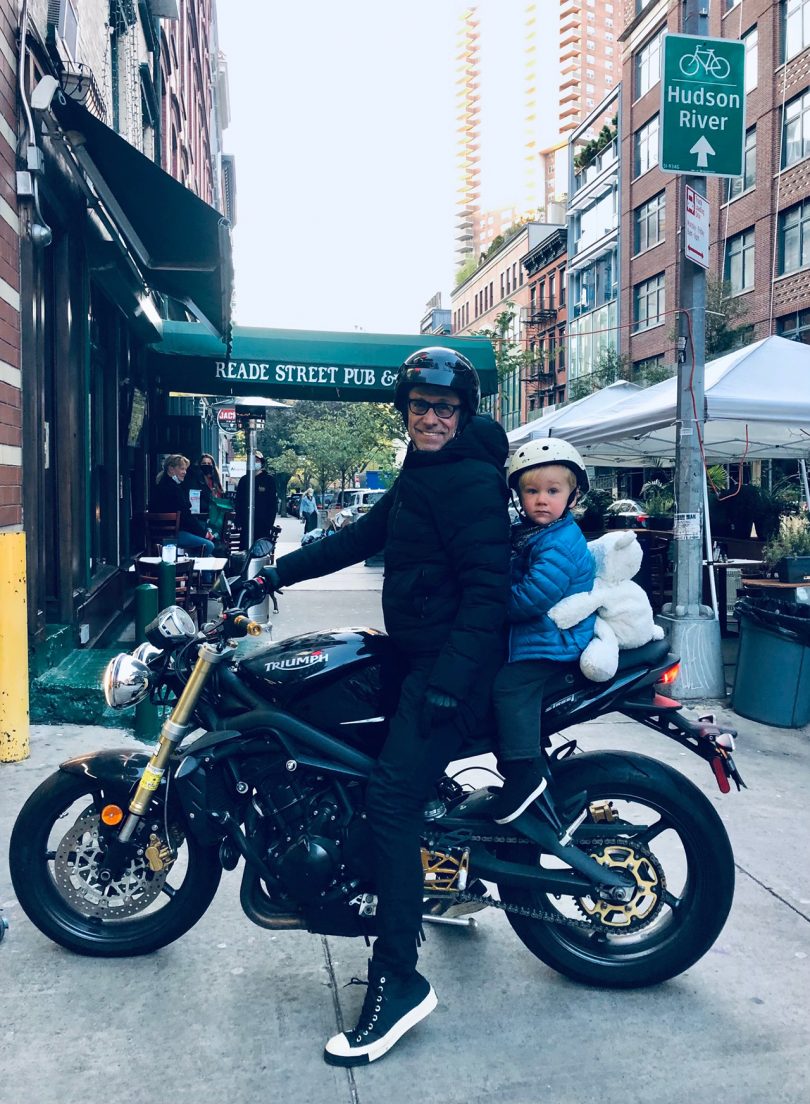 man and young child sitting on motorcycle on city street