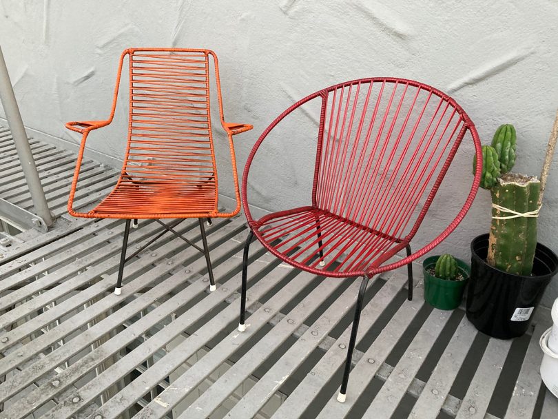 one orange chair and one red chair on slatted balcony