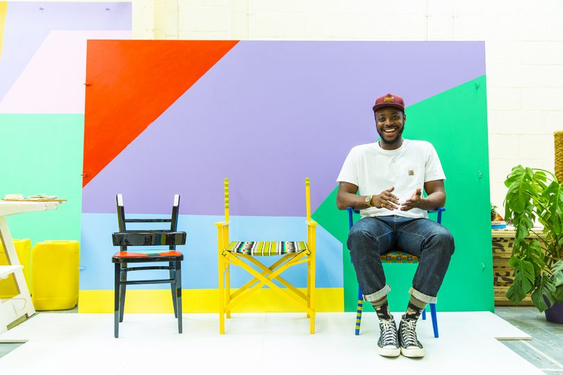 black man sitting in one of three chairs against a colorful geometric background