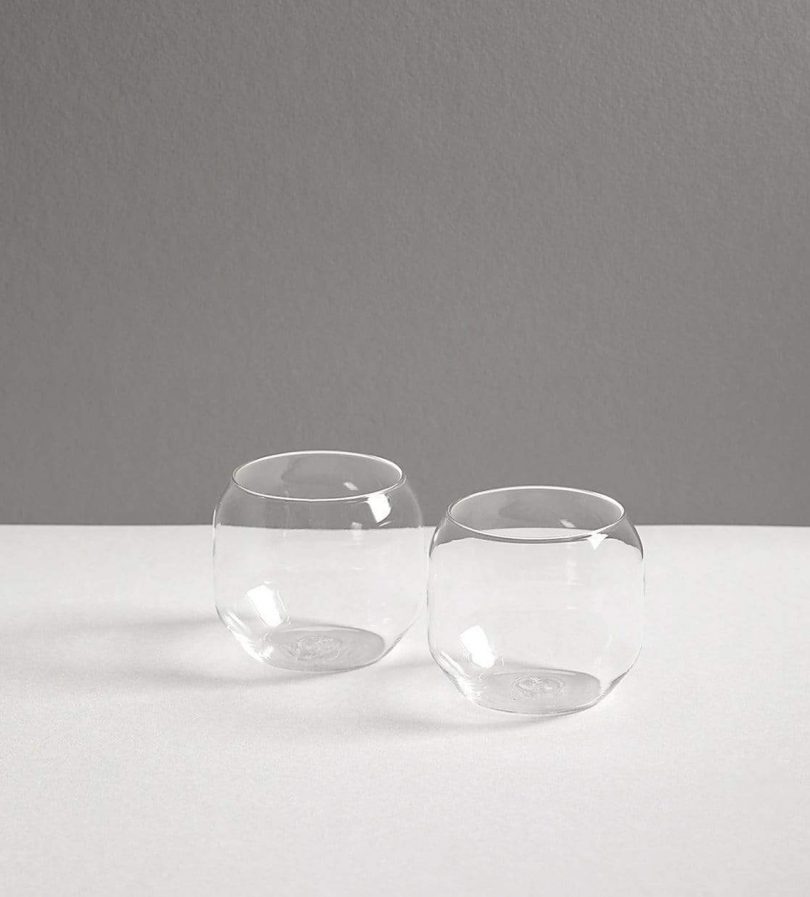 two clear glass tumblers on a white and grey background
