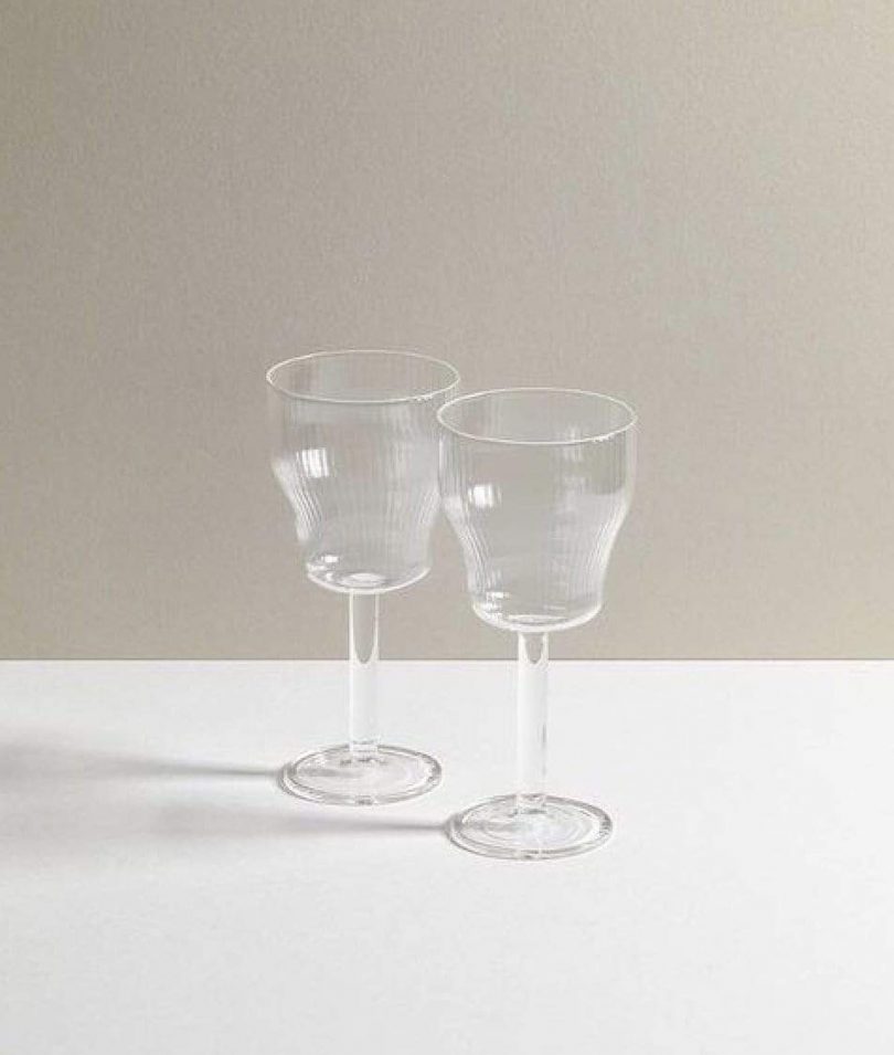 two clear wine glasses on a white and grey background