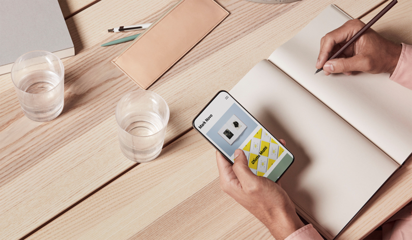 overhead photo of wood table with notebook, smartphone, and two water glasses