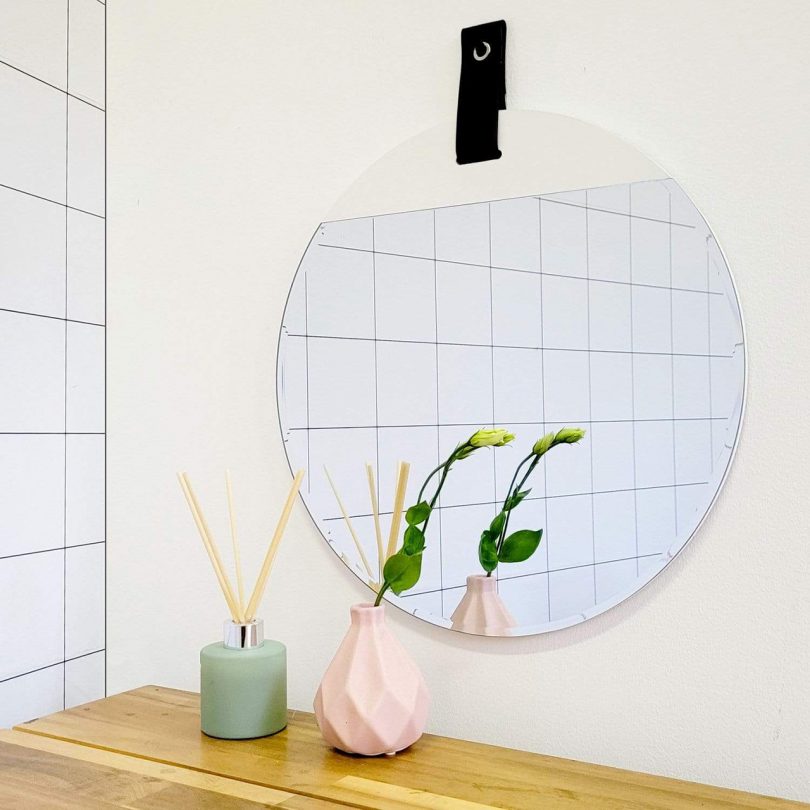 round wall mirror hanging on white wall