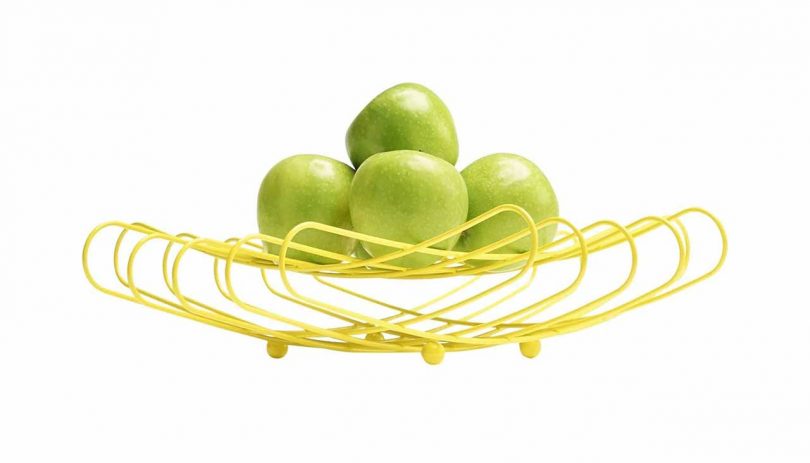 bright yellow wire fruit bowl with green apples