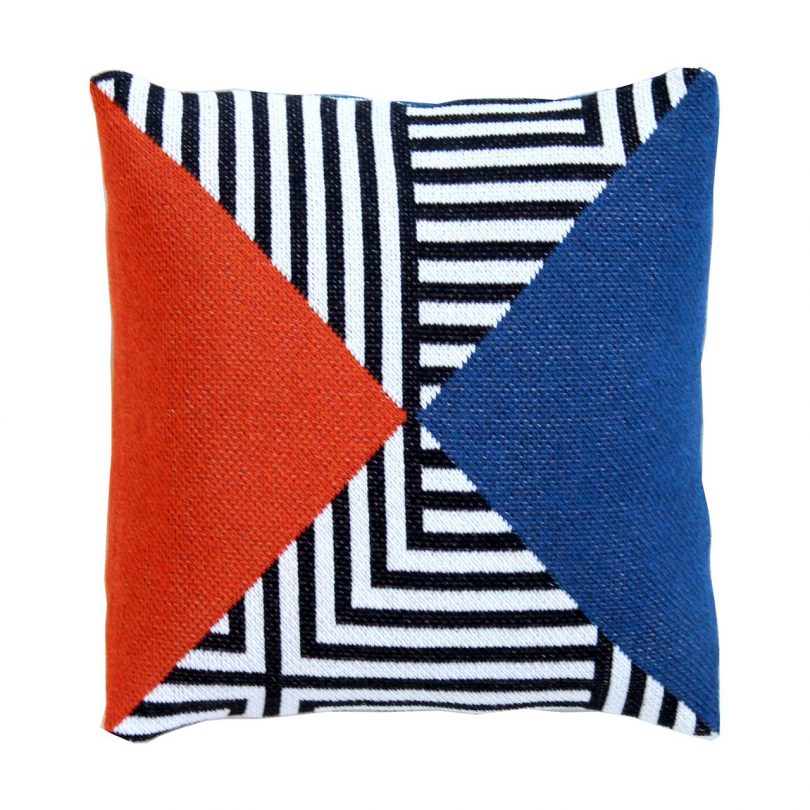 knitted pillow cover with graphic black + white pattern and blocks of red and blue