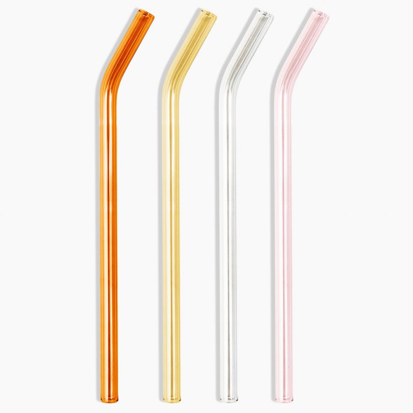 four glass straws lined up on white background