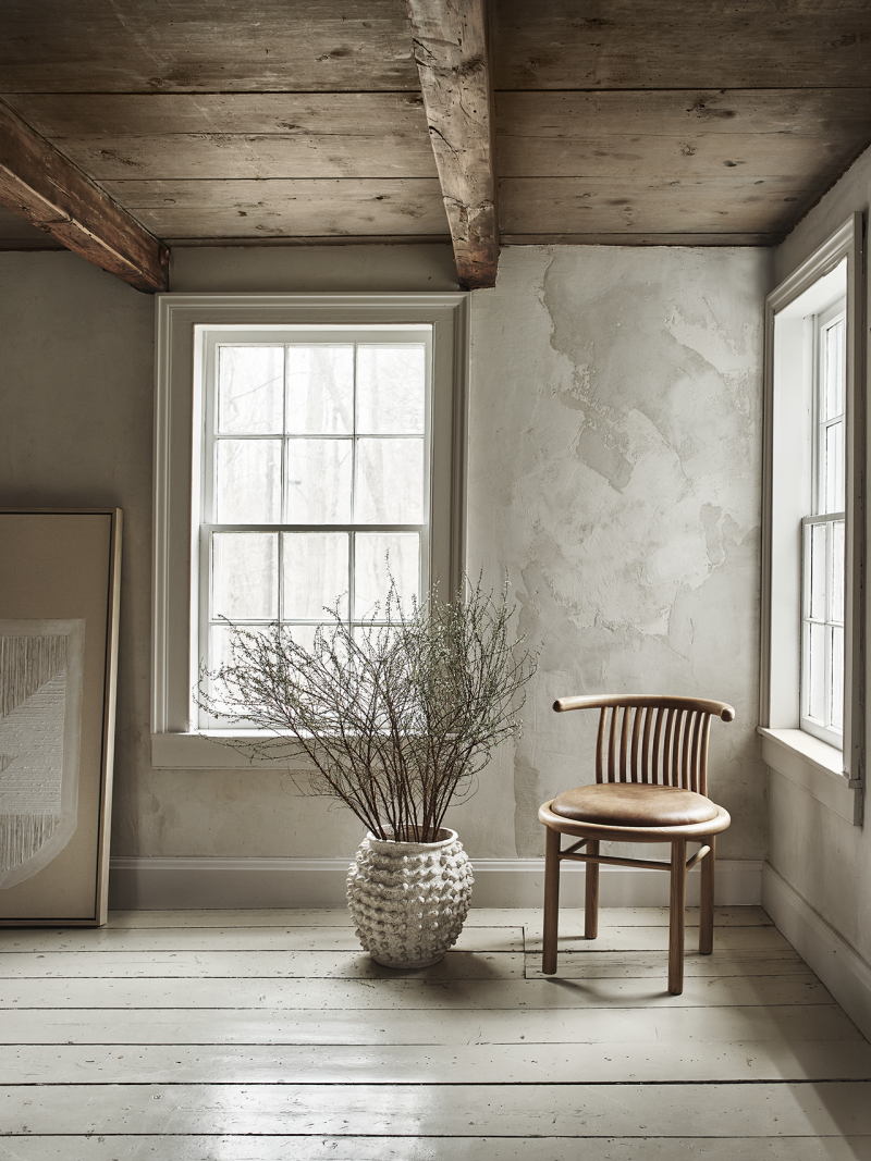 living space with window, large vase, and chair