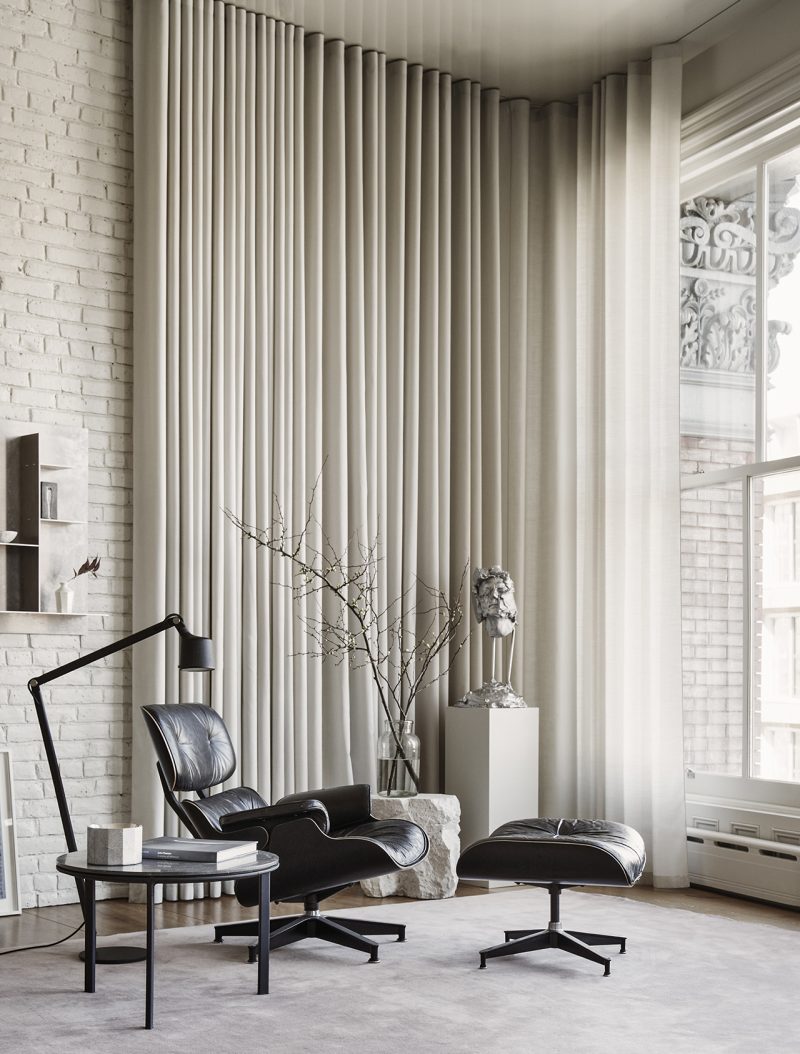 living space with Eames chair and footrest, long curtain, and large window