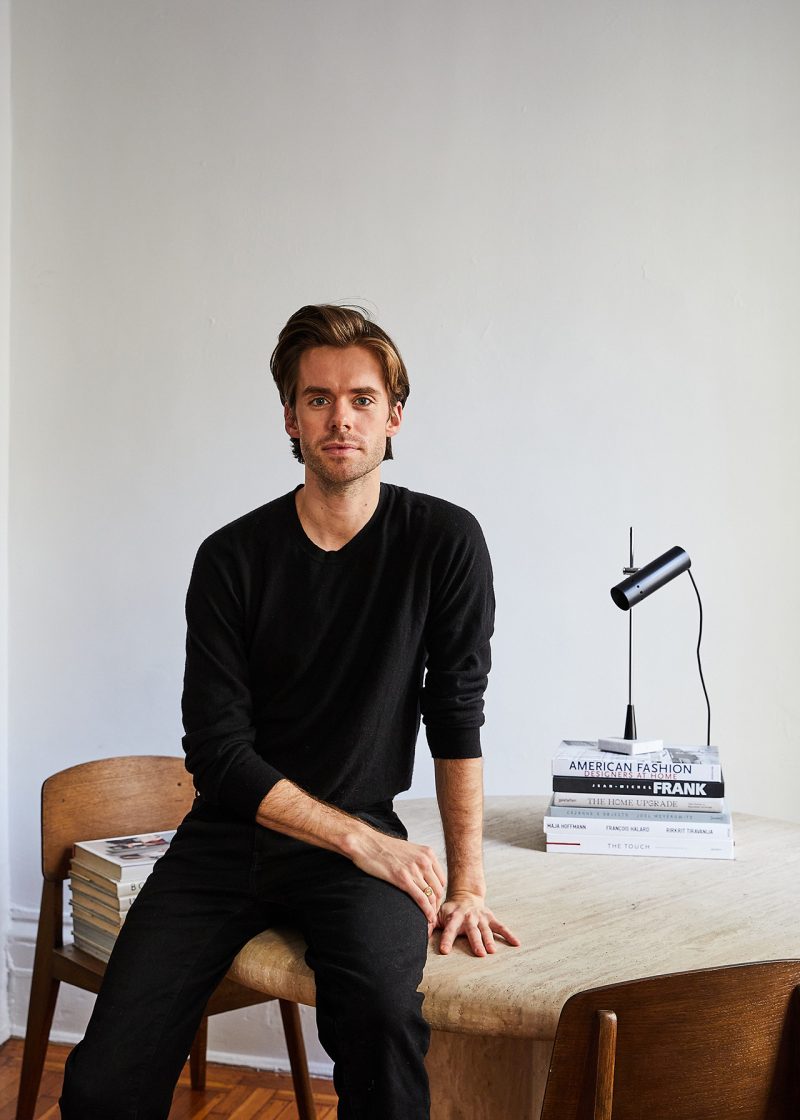 light-skinned man wearing black and sitting on workspace table