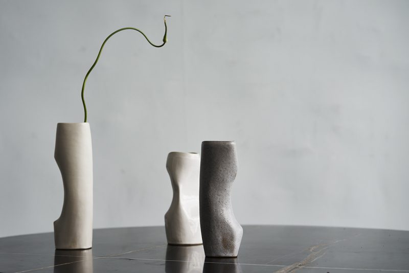 three curvaceous vases sitting on a dark reflective surface