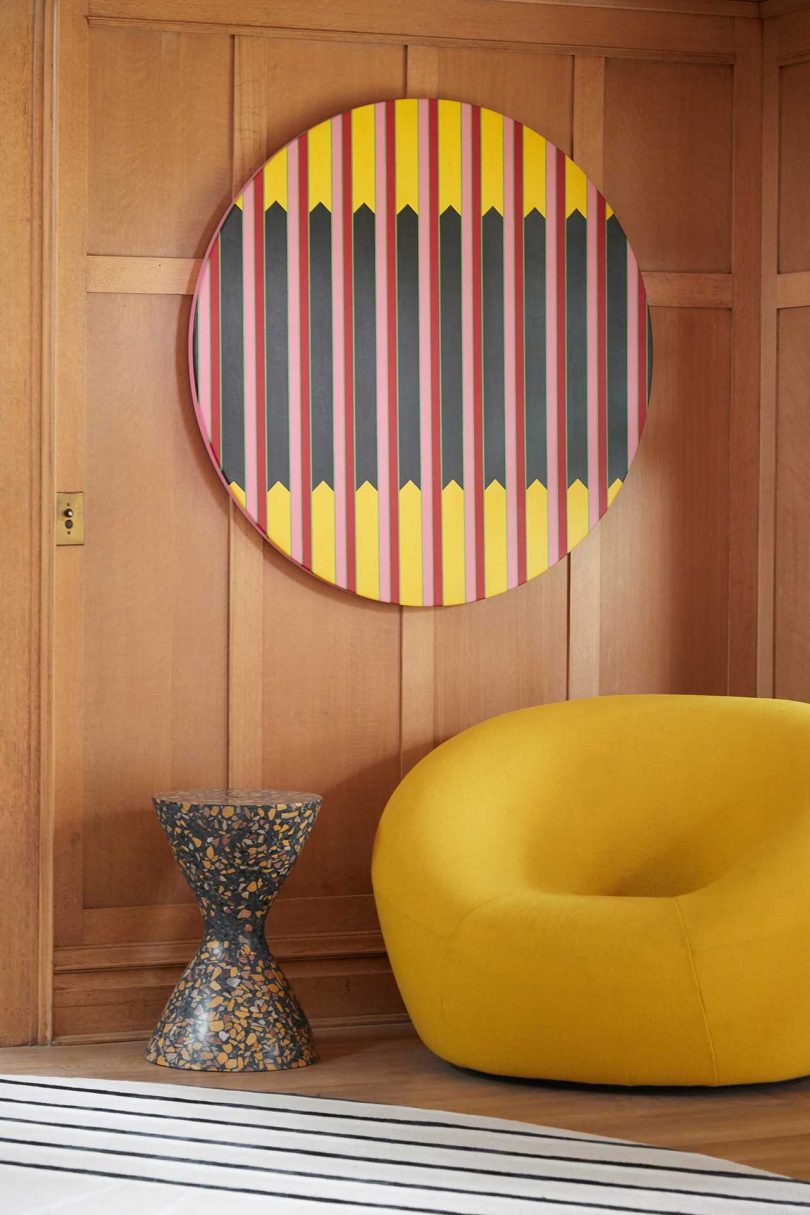 modern yellow chair in corner with circular art on wall