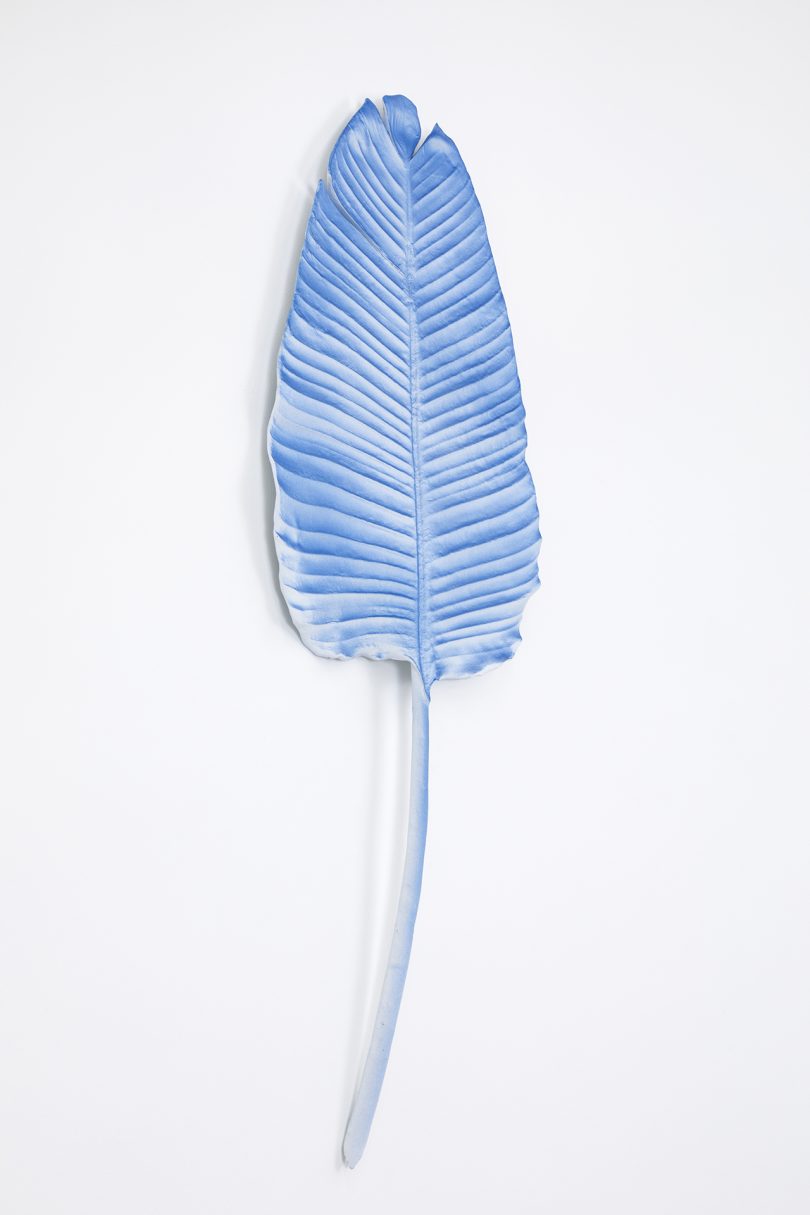 blue leaf sculpture hanging on white wall