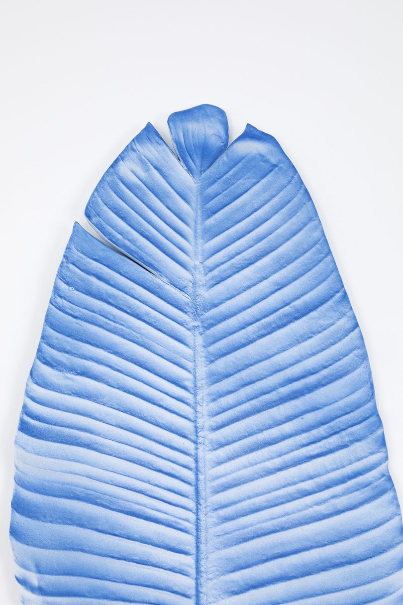 detail of blue leaf sculpture hanging on white wall