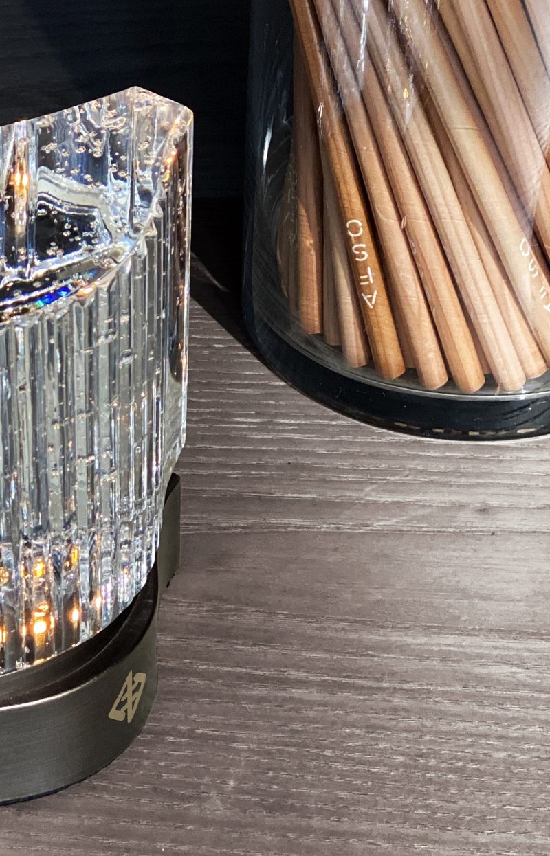 close up of glass container holding pencils and clear beverage in glass