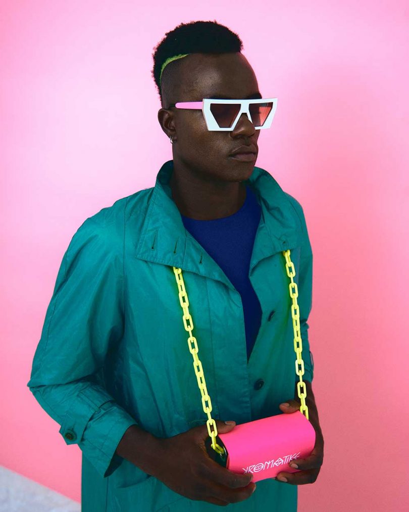 man in green jacket wearing sunglasses and pink bag