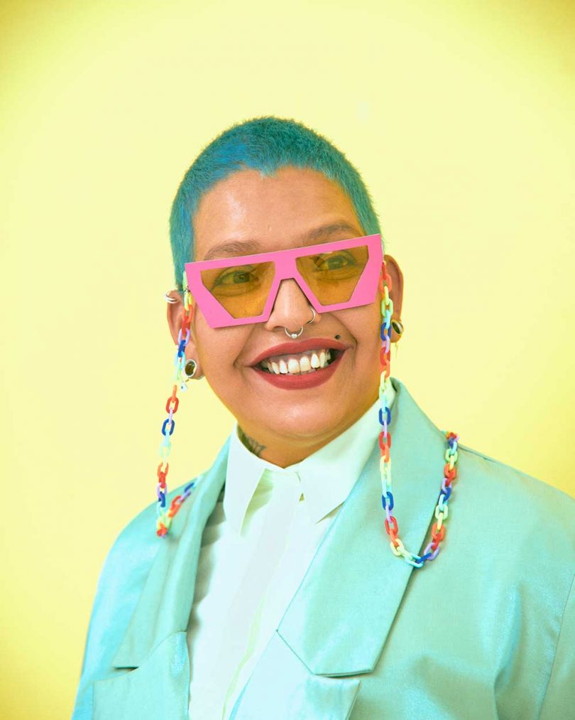girl with teal hair and pink and blue sunglasses with rainbow chain