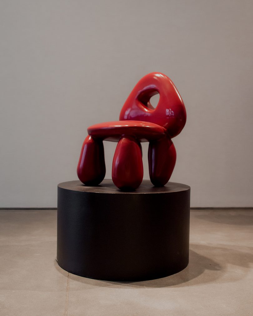 sculptural red chair on black pedestal