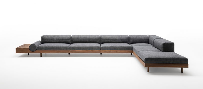 low modular outdoor sofa with wooden frame and grey upholstery on white background