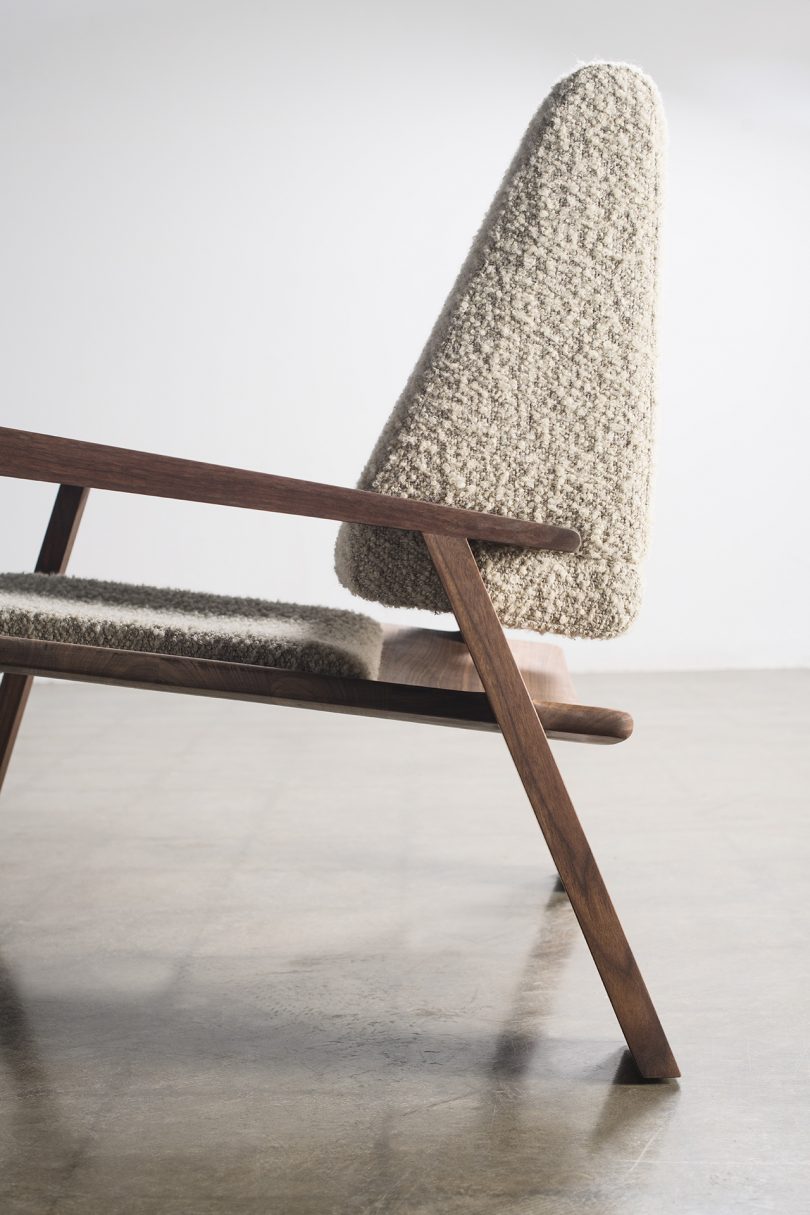 wood and upholstered armchair on cement floor in front of white wall