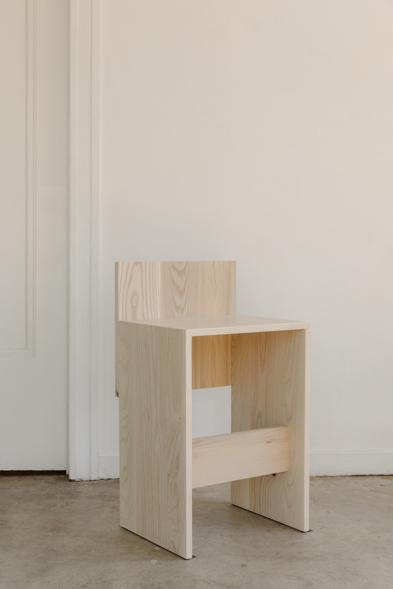 primitive wood chair on concrete floor in front of white wall