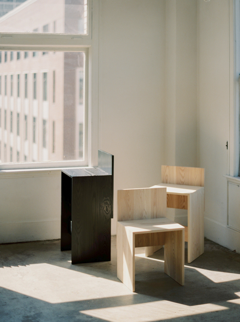 three primitive wood chairs on concrete floor in front of white wall