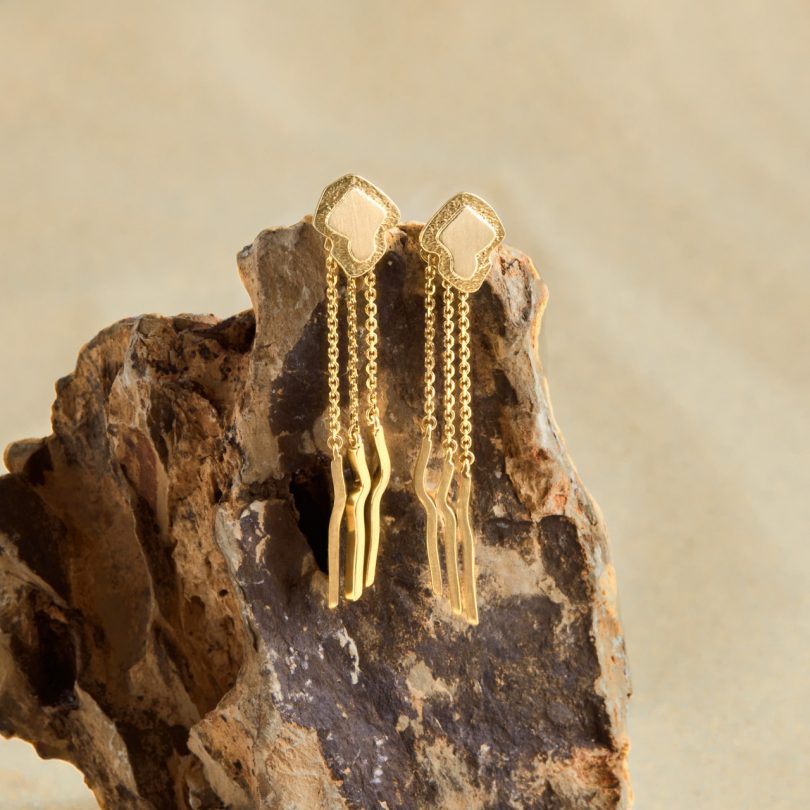 gold dangling earrings on rock
