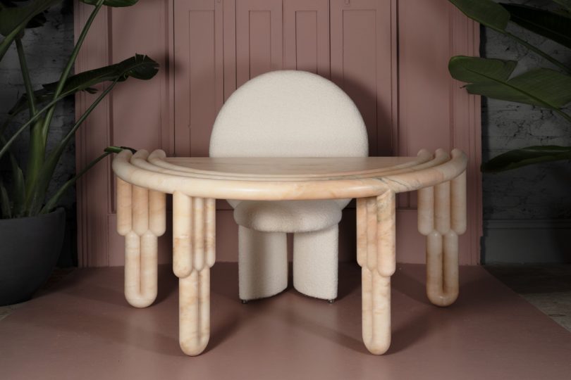 semicircular marble desk with white geometric chair behind it