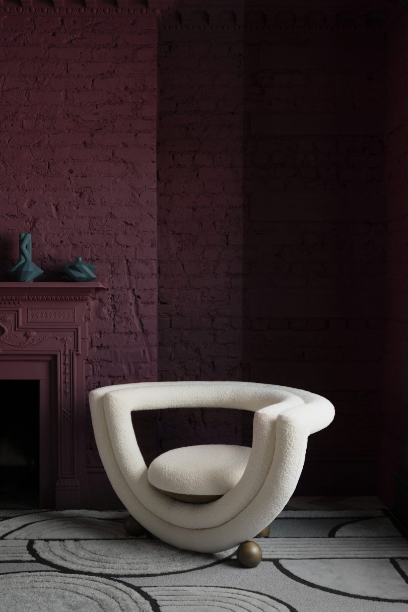 rounded white armchair in front of dark wall