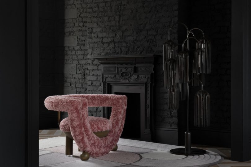 rounded pink armchair in front of dark wall