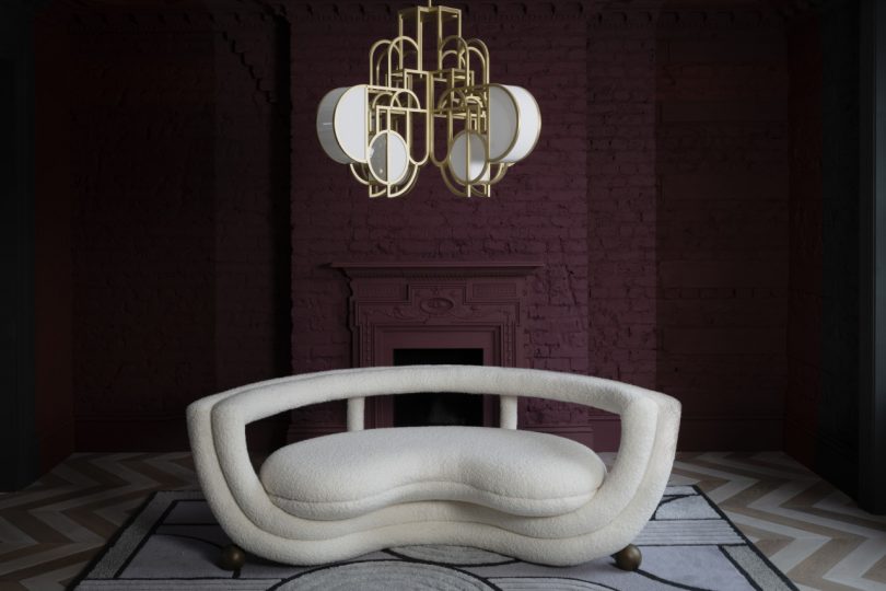 white geometric sofa sitting underneath an ornate chandelier