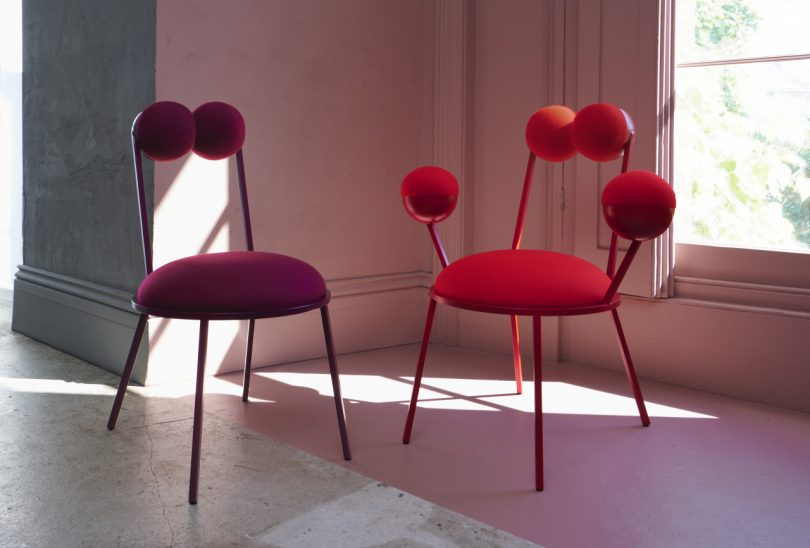 berry colored and red geometric chairs in front of a light pink wall